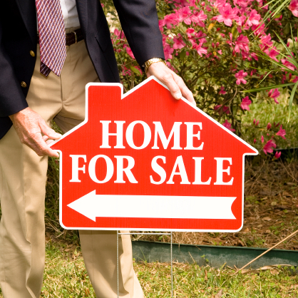 Realtor putting up for sale sign in anticipation of open house caravan